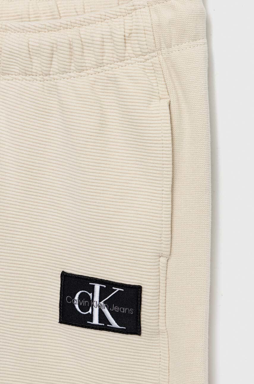 Calvin Klein Jeans Detské bavlnené tepláky béžová farba s nášivkou - Pepit.sk